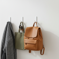 Self-adhesive wall hooks mounted on a wall holding keys, bags, and coats